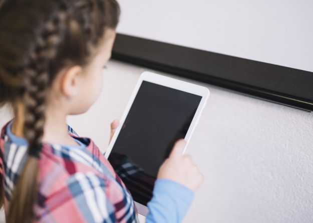 little girl holding a tablet or an ipad and staring at it